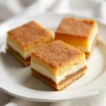 Sopapilla cheesecake slice with cinnamon sugar and honey drizzle, served on a plate.
